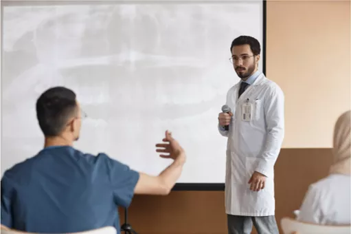 back screen with a radiograph of teeth with a teacher standing in front speaking to a student 